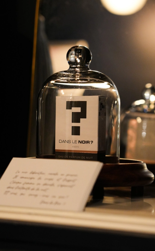 Flacon de parfum sous cloche, mettant en valeur les ateliers parfum Dans le Noir ?