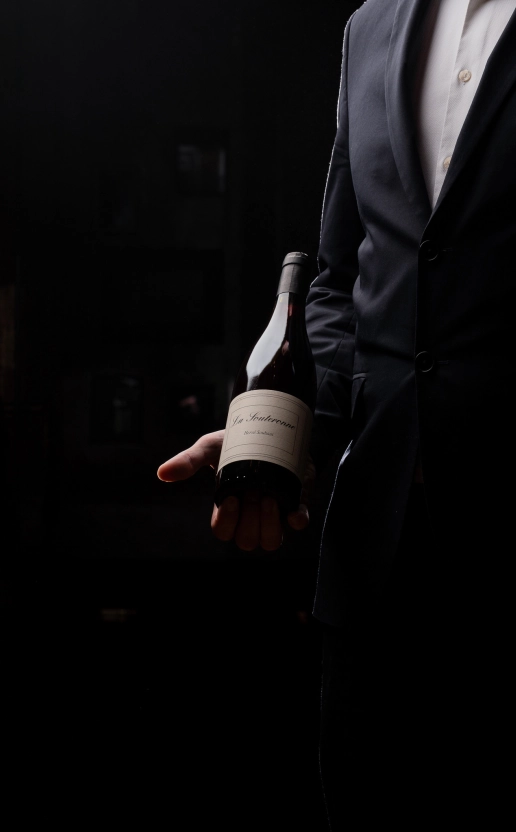 Homme tenant une bouteille de vin lors d'un atelier de dégustation au restaurant Dans le Noir ?