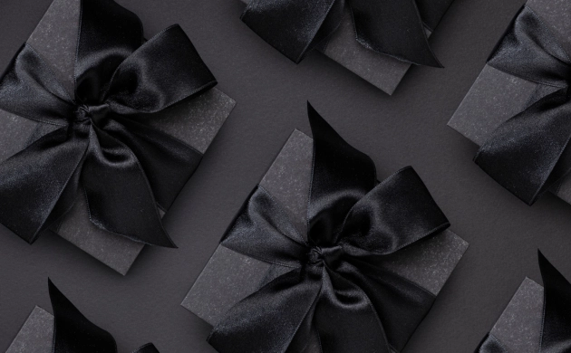 Boîte cadeau noire élégante avec un nœud en satin noir, disposée sur un fond sombre pour un effet luxueux et raffiné.