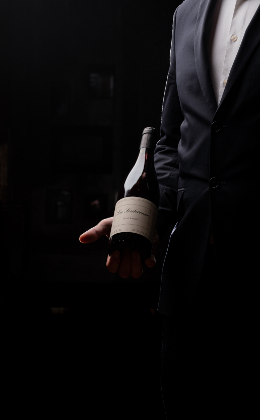 Man holding a bottle of wine during a tasting workshop at the Dans le Noir ? restaurant.