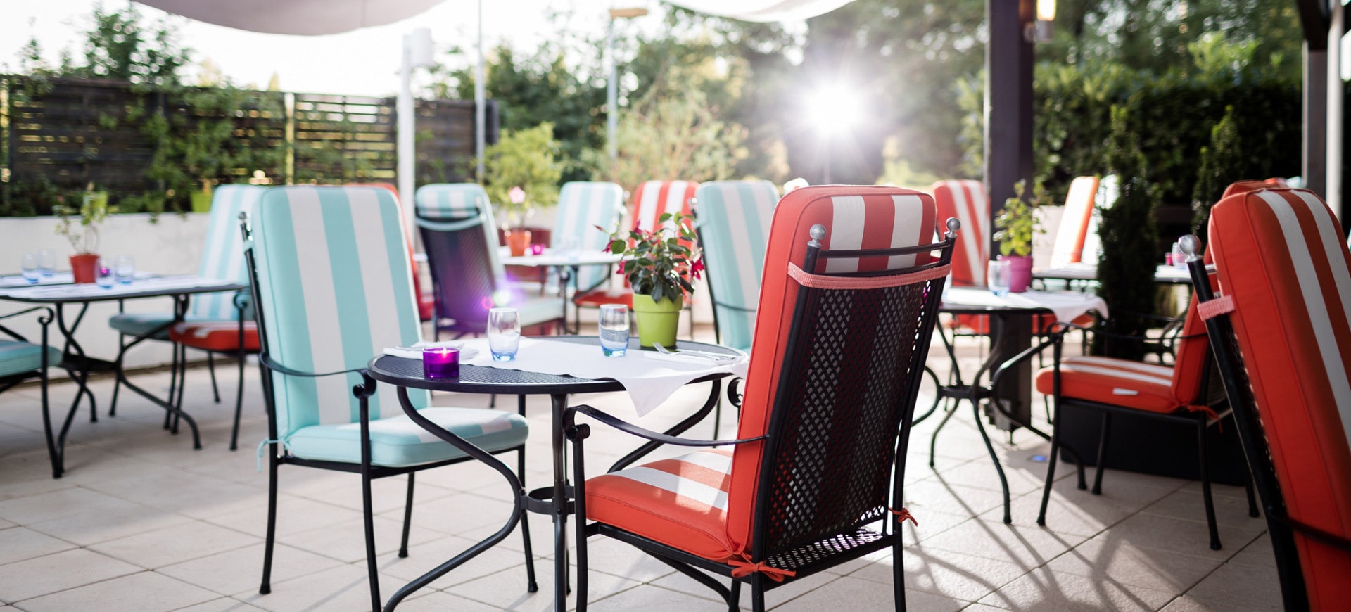 Sunny terrace of a restaurant with colorful chairs and a warm atmosphere, perfect for outdoor dining