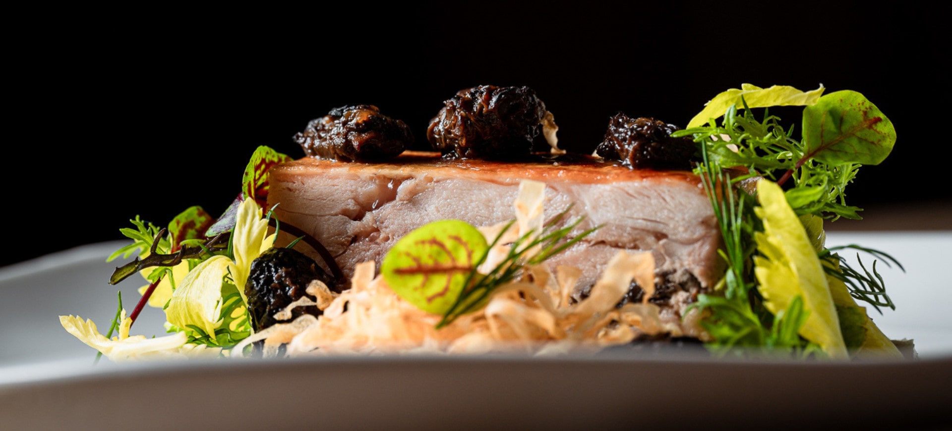 A refined gastronomic dish featuring a tender, melt-in-the-mouth cut of meat, enhanced with condiments and fresh herbs, elegantly plated.