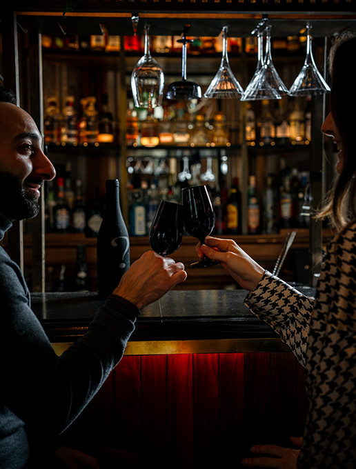 Deux personnes trinquant au bar du restaurant Dans le Noir ?