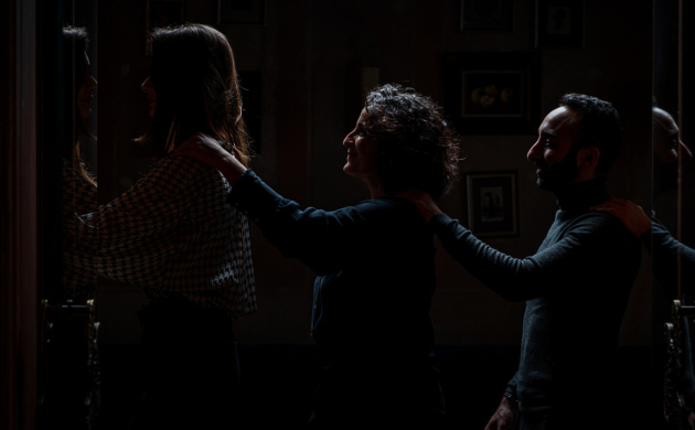 Clients formant une file en se guidant par l'épaule, découvrant l'expérience immersive du restaurant Dans le Noir ? avant de dîner dans l'obscurité totale.