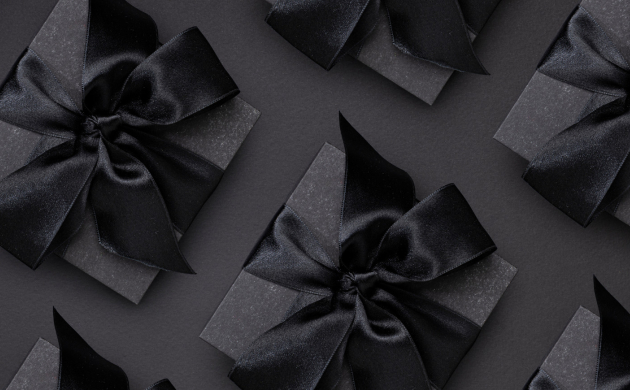 Boîte cadeau noire élégante avec un nœud en satin noir, disposée sur un fond sombre pour un effet luxueux et raffiné.