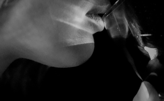 Gros plan en noir et blanc d'une personne portant un verre à ses lèvres, illustrant l'expérience immersive de dégustation sensorielle à l'aveugle.